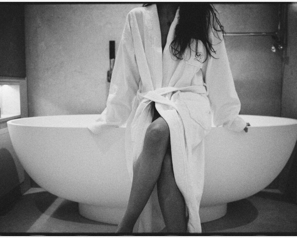 Artistic black and white photograph by Tiffany Roubert of writer and presenter Roma Wells preparing for a bathing ritual in a Japanese-inspired hotel bathroom at The Prince Akatoki.