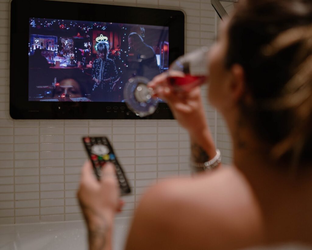 Luxury hotel bathroom with integrated television beside a deep soaking bath.